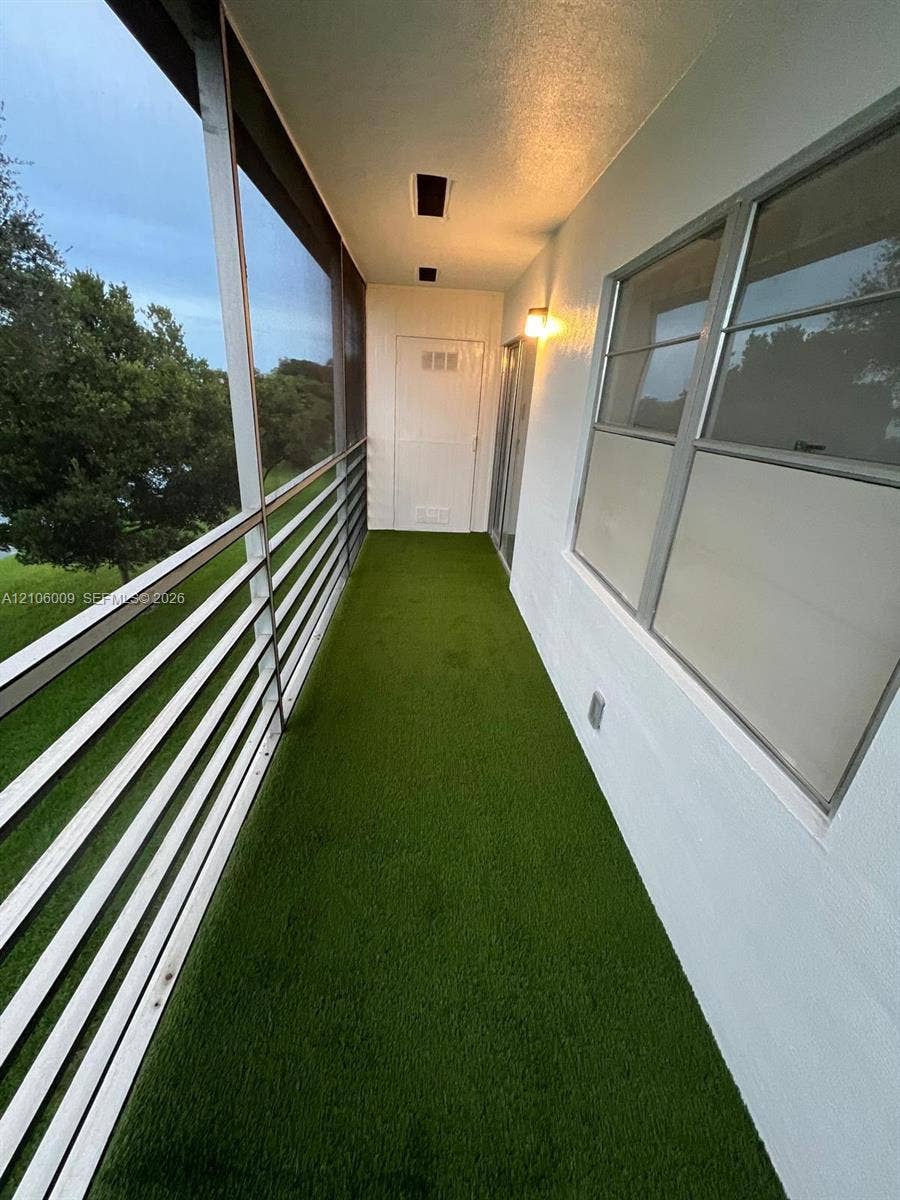 495 Fanshaw L, Boca Raton, FL 33434 Screen-enclosed balcony featuring artificial turf flooring, metal railing, and recessed ceiling lighting