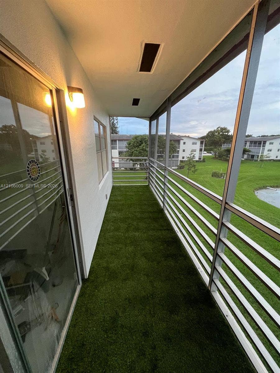 495 Fanshaw L, Boca Raton, FL 33434 Screened-in balcony featuring synthetic turf flooring, horizontal metal railing, and recessed ceiling lighting