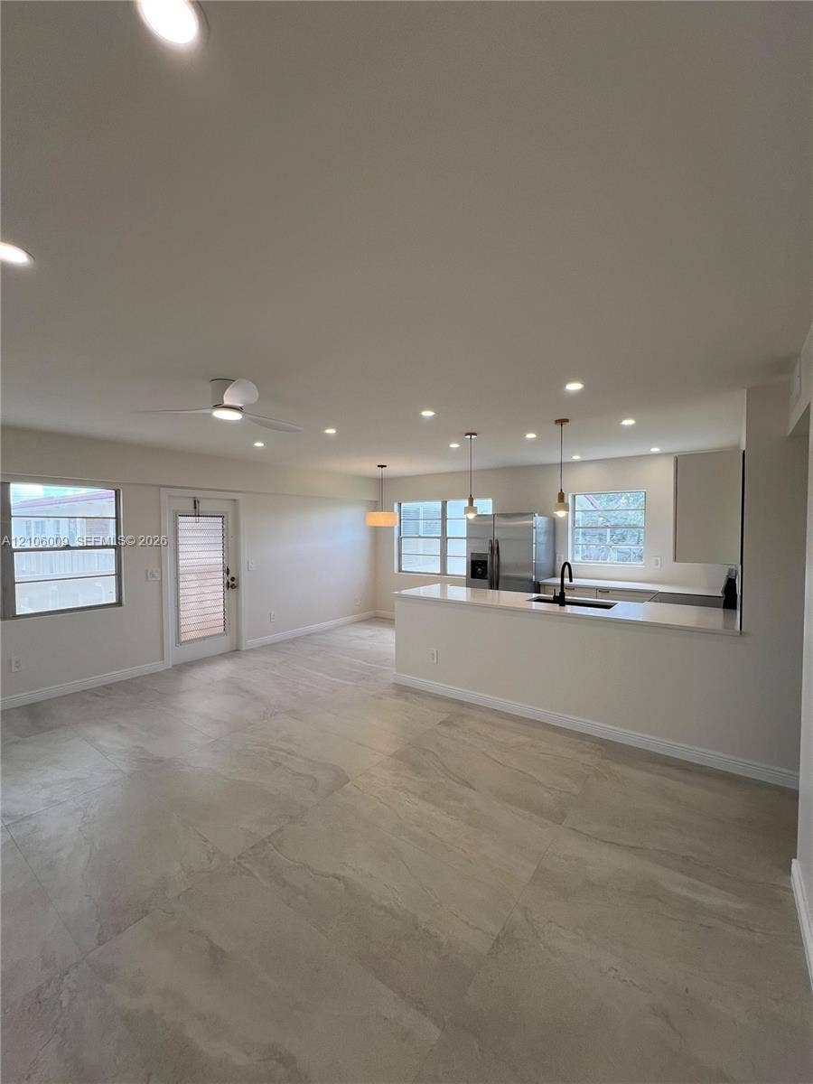 495 Fanshaw L, Boca Raton, FL 33434 Open-concept interior featuring large-format tile flooring, recessed lighting, kitchen with quartz-surfaced island and bar seating, and stainless-steel appliances