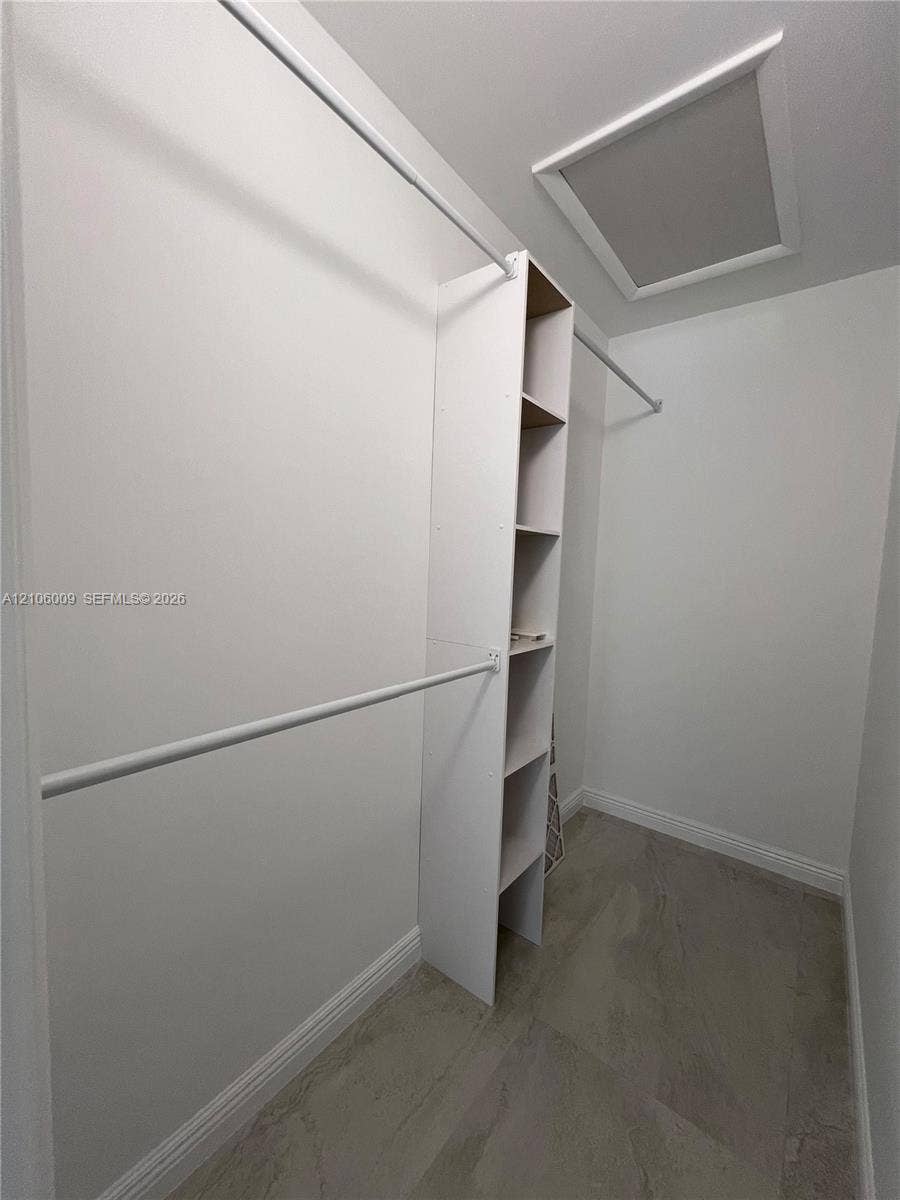 495 Fanshaw L, Boca Raton, FL 33434 Walk-in closet featuring white built-in shelving, dual-tier hanging rods, and neutral-toned flooring