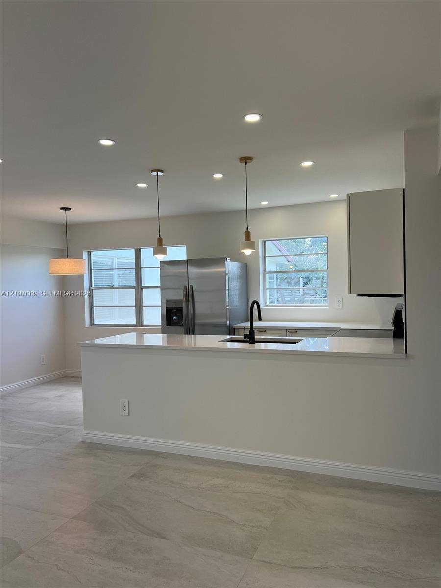 495 Fanshaw L, Boca Raton, FL 33434 Kitchen featuring a quartz peninsula, stainless steel refrigerator, matte black faucet, pendant lighting, and large-format tile flooring