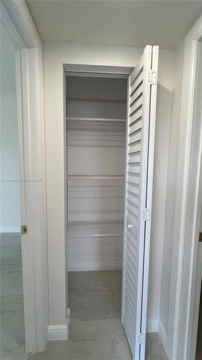 495 Fanshaw L, Boca Raton, FL 33434 Storage closet featuring white louvered bifold doors and integrated wire shelving