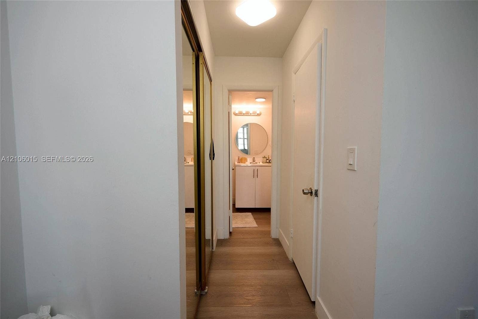 2851 NE 183rd Street, #1109E, Aventura, FL 33160 Hallway featuring wood-finish flooring, floor-to-ceiling mirrored sliding closet doors, and flush-mount ceiling lighting
