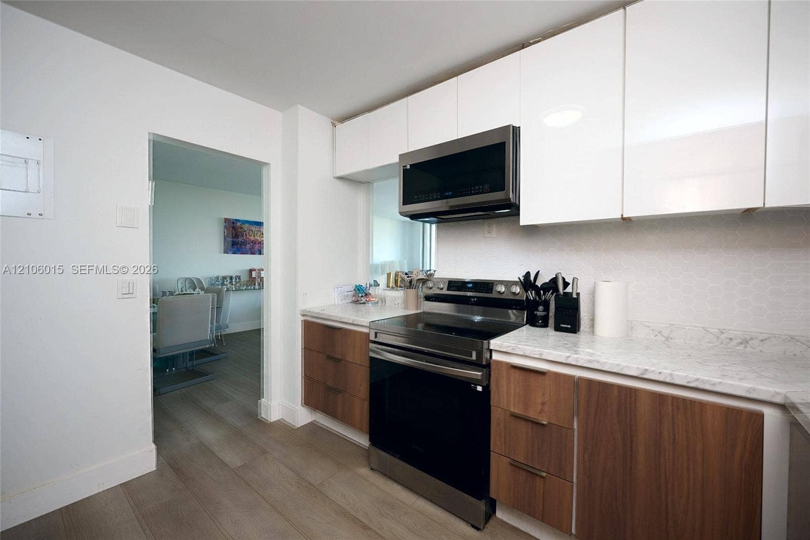 2851 NE 183rd Street, #1109E, Aventura, FL 33160 Kitchen featuring two-tone flat-panel cabinetry, light-toned stone-finish countertops, geometric tile backsplash, and stainless steel appliances