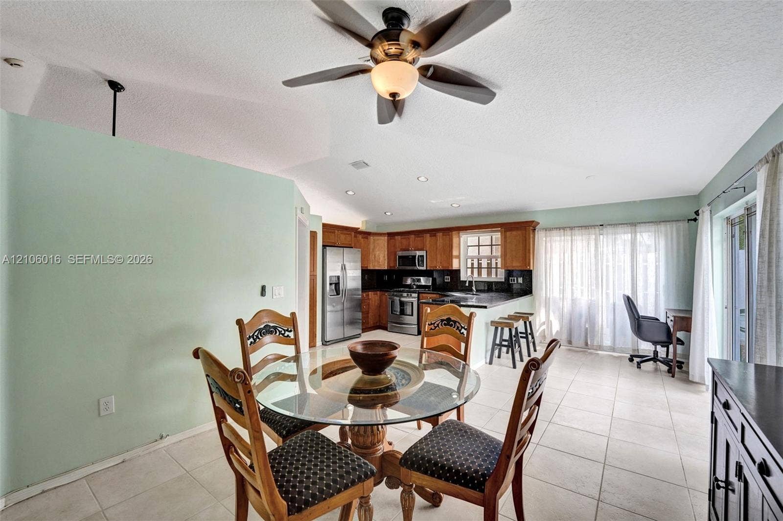 631 NW 135th Terrace, Plantation, FL 33325 Vaulted ceiling featuring a central ceiling fan with integrated lighting, wood cabinetry, stainless steel appliances, ceramic tile flooring, and recessed lighting