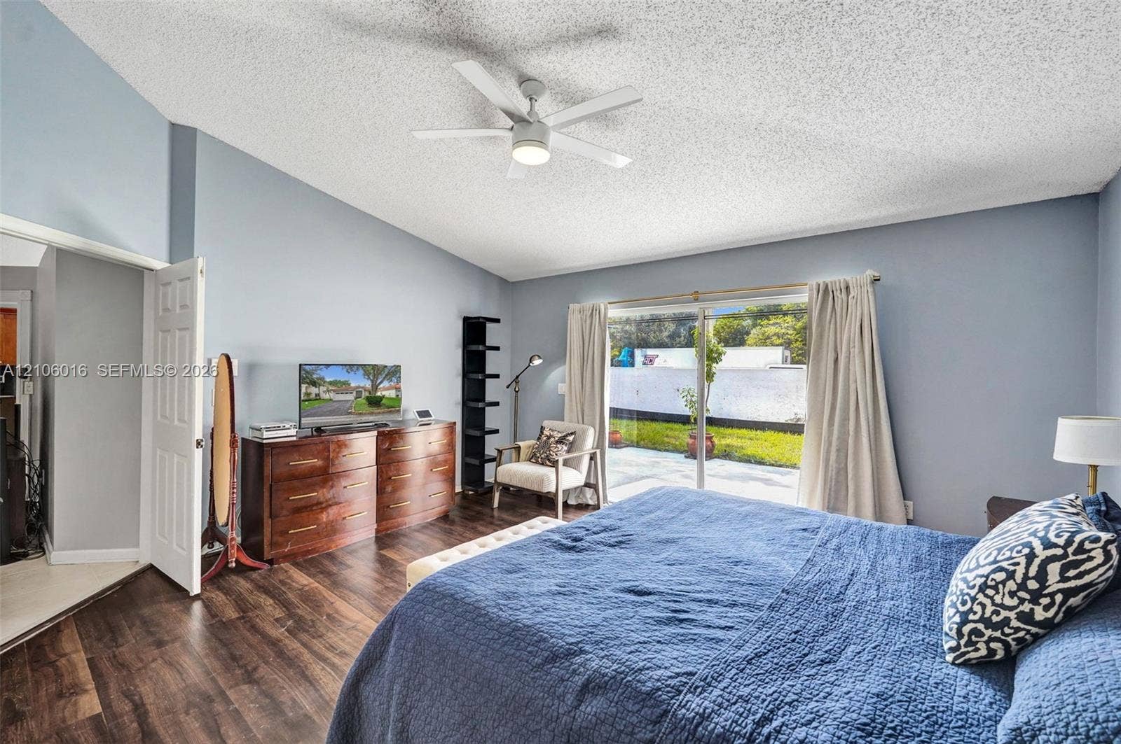 631 NW 135th Terrace, Plantation, FL 33325 Vaulted ceiling with a central multi-blade ceiling fan, wood-finish flooring, and sliding glass doors providing outdoor access