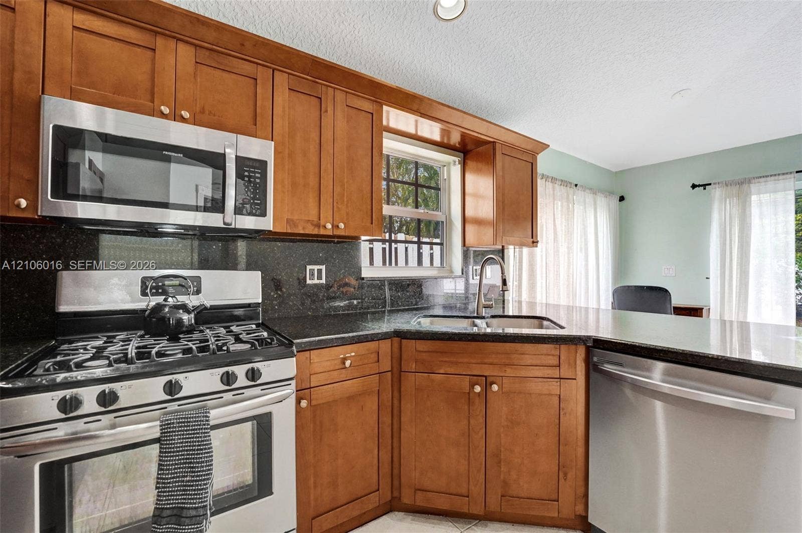 631 NW 135th Terrace, Plantation, FL 33325 Kitchen featuring wood cabinetry, stone countertops, stainless steel gas range, over-the-range microwave, and stainless steel dishwasher