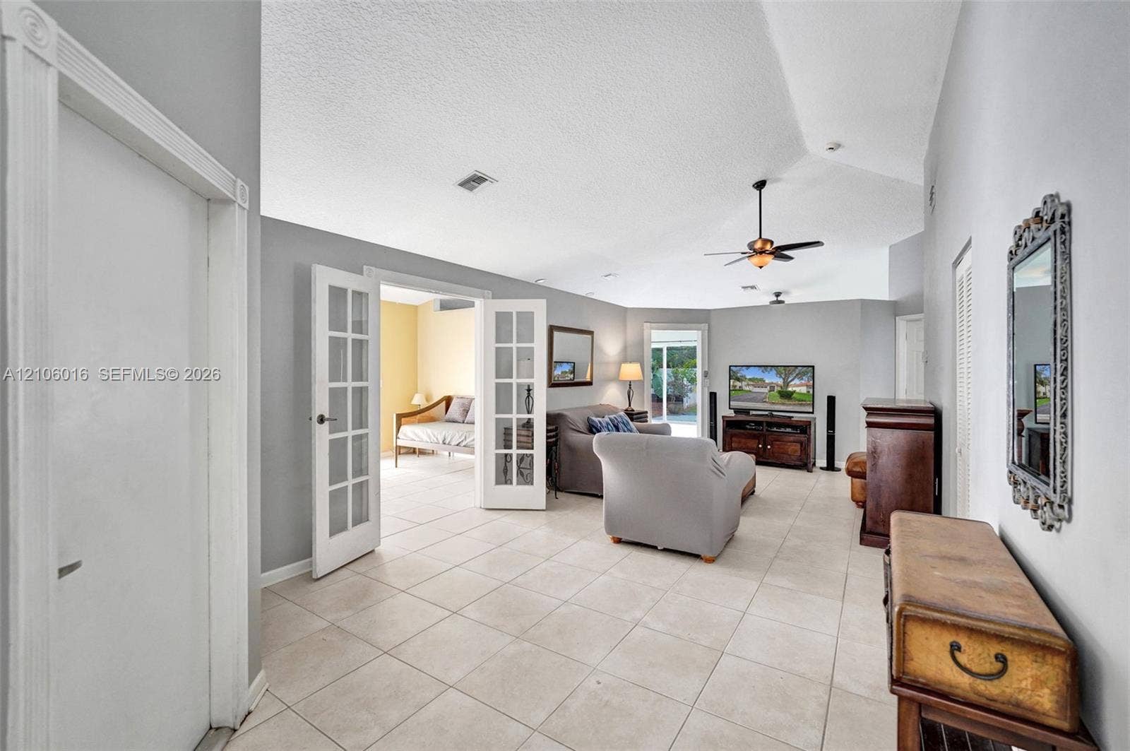 631 NW 135th Terrace, Plantation, FL 33325 Living area featuring vaulted ceilings, light-toned tile flooring, French doors with glass panes, and a ceiling fan with light fixture