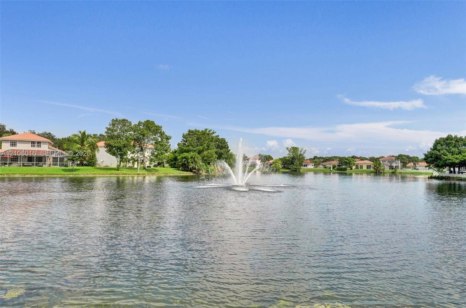 631 NW 135th Terrace, Plantation, FL 33325 Waterfront pond featuring a central fountain, manicured lawn, and mature landscaping