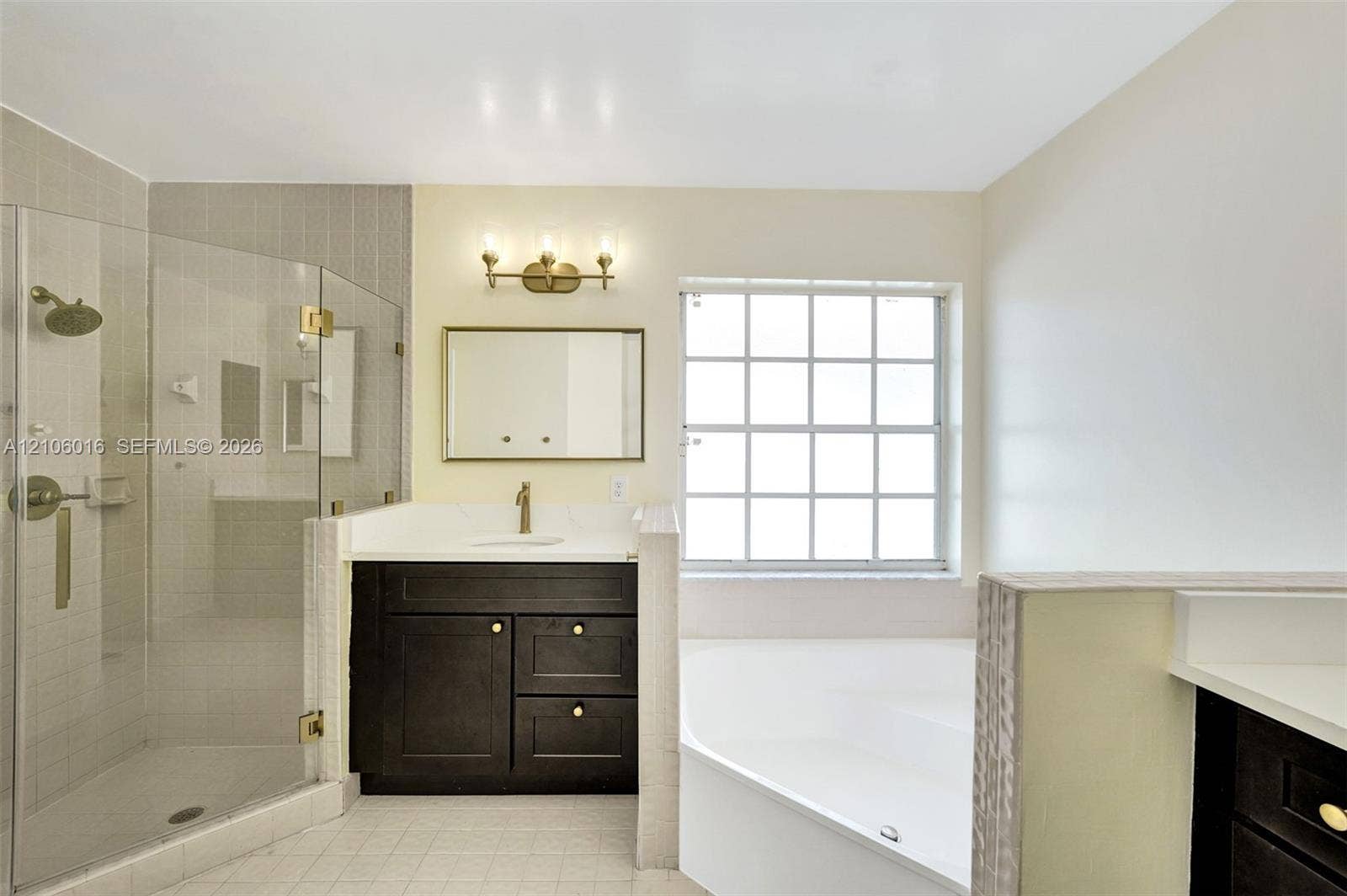 631 NW 135th Terrace, Plantation, FL 33325 Bathroom featuring a glass-enclosed shower, a dark-finish vanity with a light-tone countertop, a soaking tub, and a multi-pane window