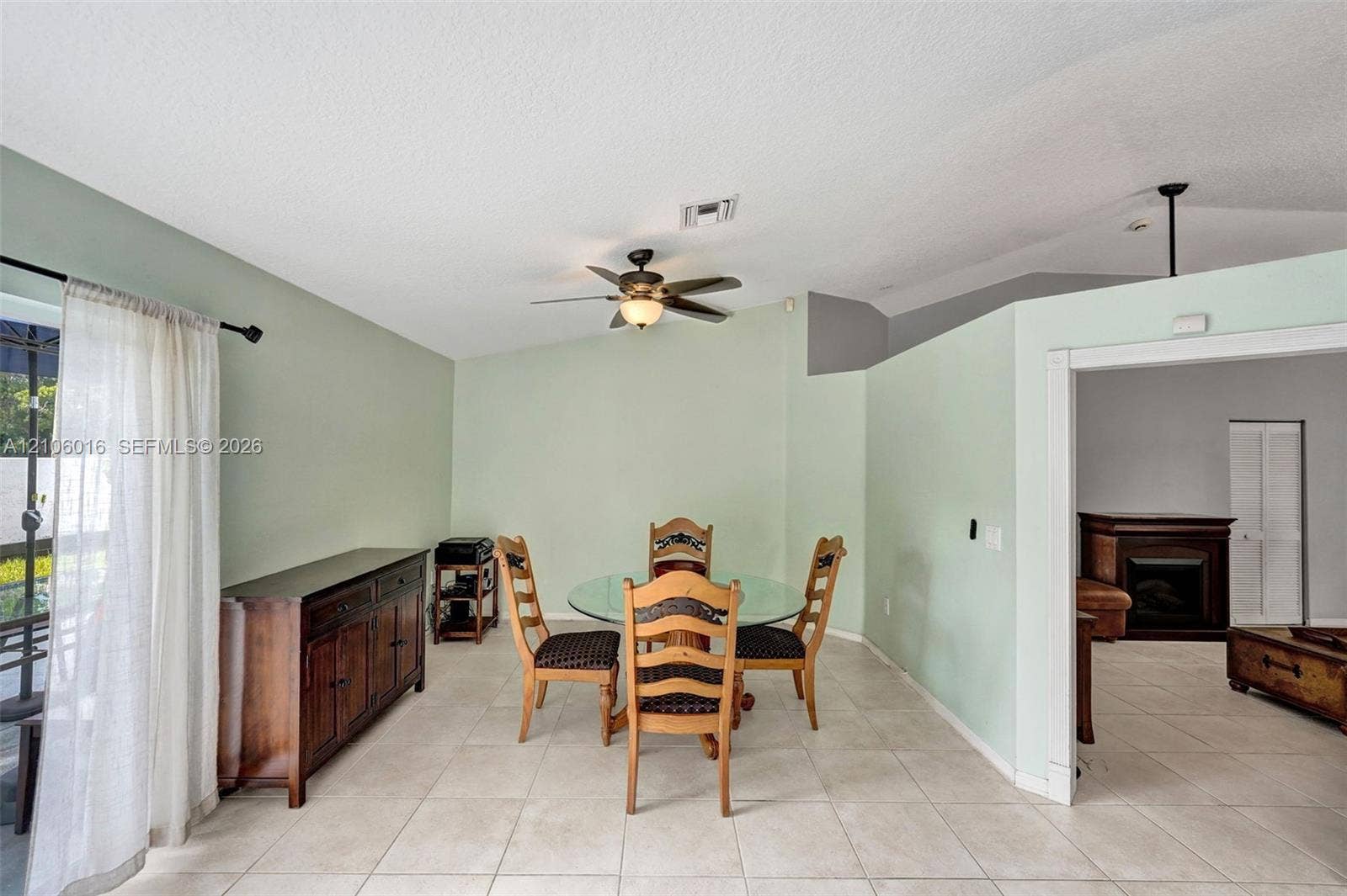 631 NW 135th Terrace, Plantation, FL 33325 Vaulted ceilings, neutral ceramic tile flooring, ceiling fan with integrated lighting, sliding glass door, and fireplace