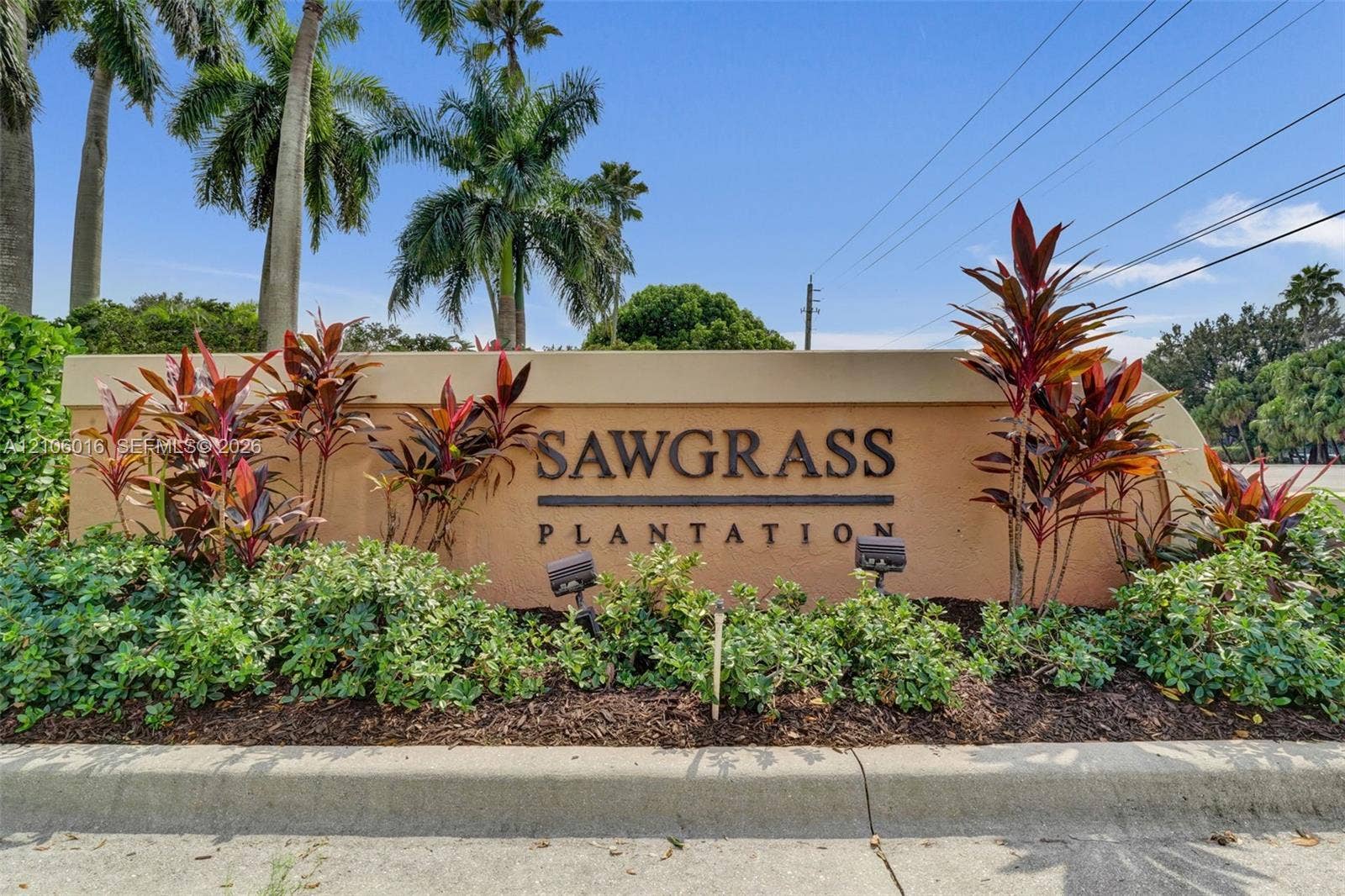 631 NW 135th Terrace, Plantation, FL 33325 Community entrance monument featuring stucco masonry construction, dimensional lettering, landscape lighting, and mature tropical foliage