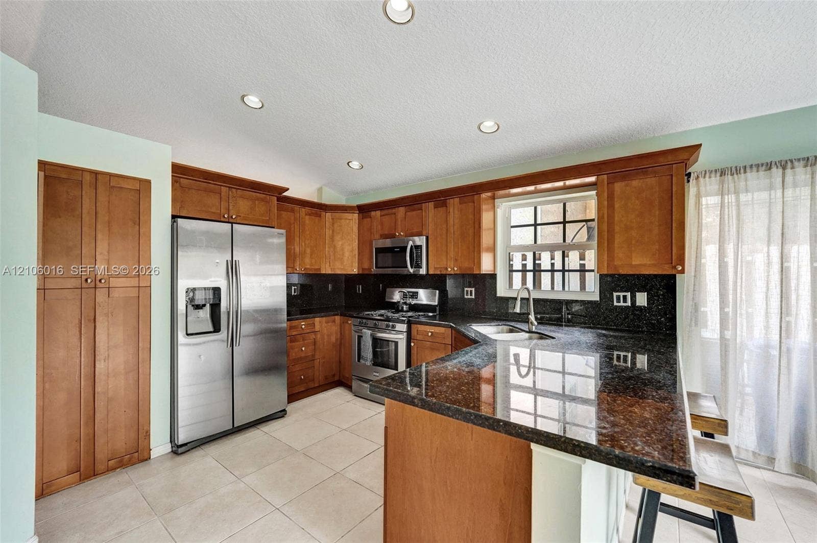 631 NW 135th Terrace, Plantation, FL 33325 Kitchen featuring wood cabinetry, stone countertops, stainless steel appliances, tiled flooring, and recessed lighting