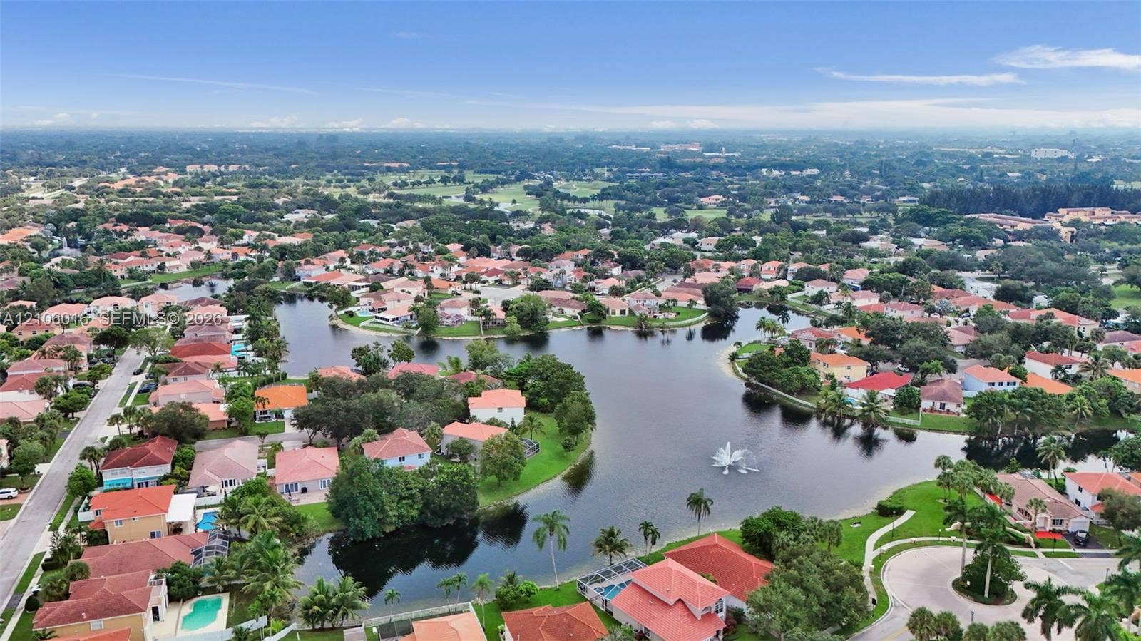 631 NW 135th Terrace, Plantation, FL 33325 Aerial perspective featuring a community lake, central fountain, paved street network, and mature landscaping