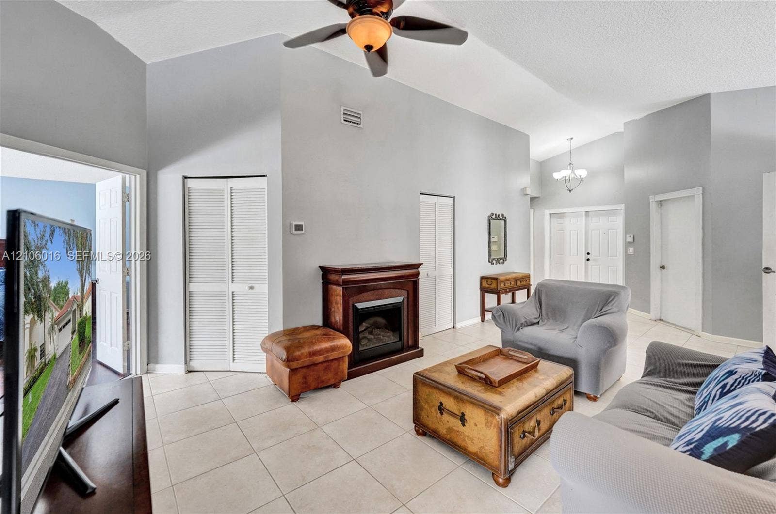 631 NW 135th Terrace, Plantation, FL 33325 Living area featuring vaulted ceilings, tile flooring, a fireplace, and a ceiling fan