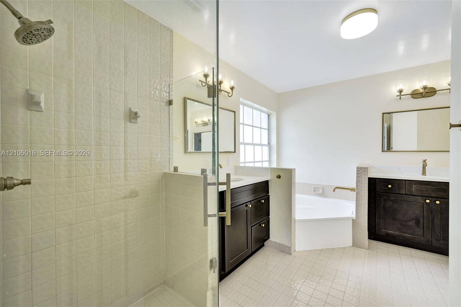 631 NW 135th Terrace, Plantation, FL 33325 Bathroom featuring a walk-in shower with glass enclosure, dual dark-finish vanities with light-toned solid surface countertops, and a built-in soaking tub