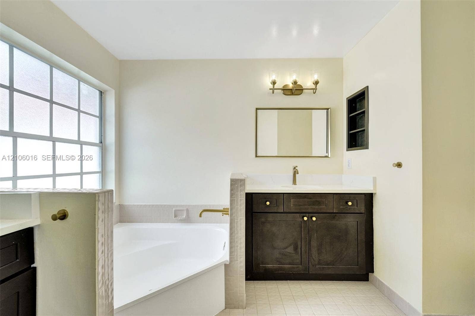 631 NW 135th Terrace, Plantation, FL 33325 Bathroom featuring a soaking tub, a single-sink vanity with a solid-surface countertop, dark cabinetry, and a wall-mounted light fixture