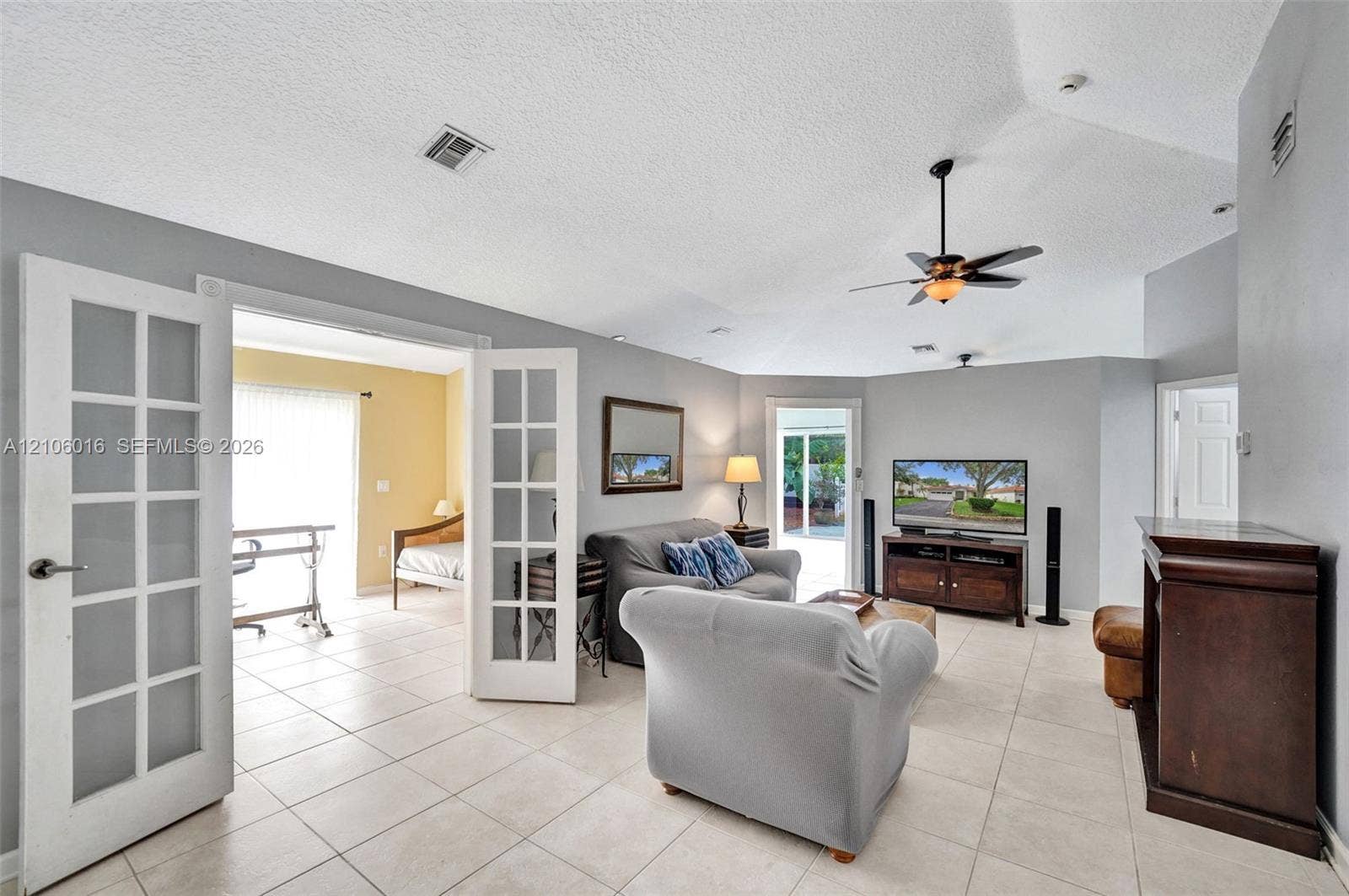 631 NW 135th Terrace, Plantation, FL 33325 Living area featuring vaulted ceilings, light-tone tile flooring, French doors, and dual ceiling fans