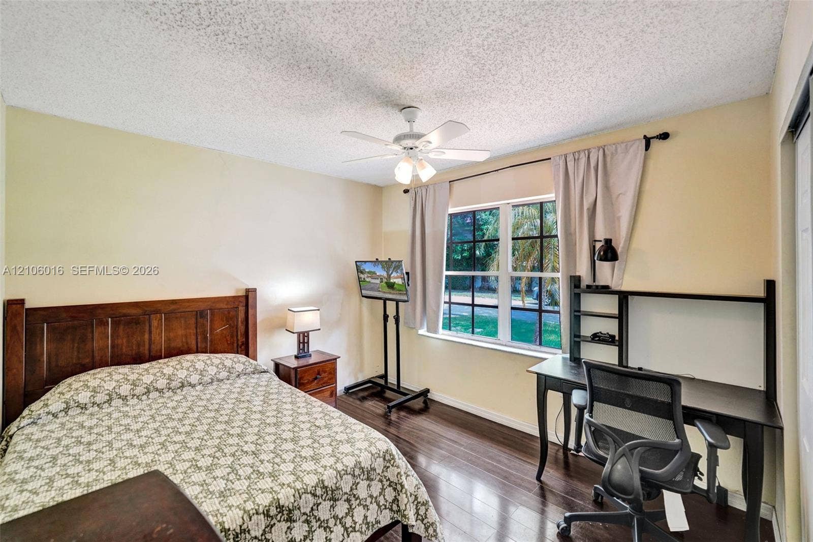 631 NW 135th Terrace, Plantation, FL 33325 Room featuring wood-finish flooring, a multi-pane window with a curtain rod, and a ceiling-mounted light fixture with a fan