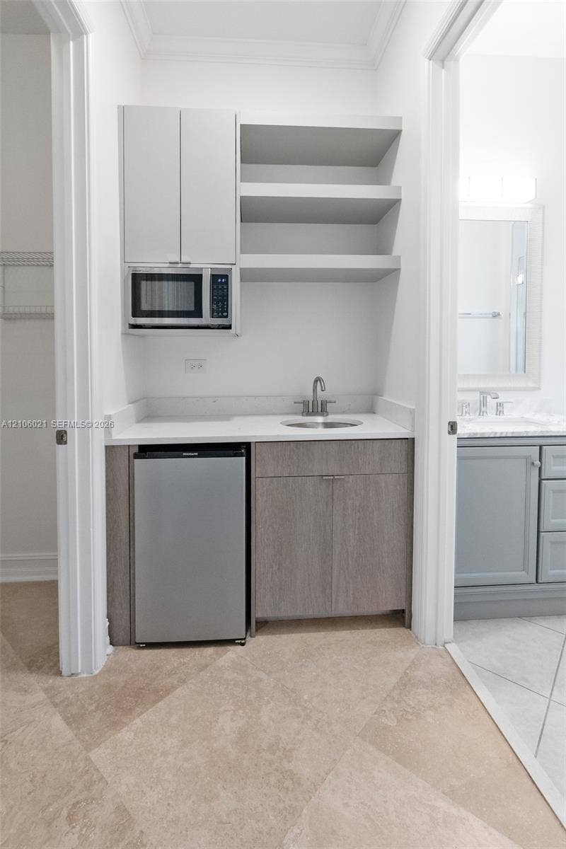 19510 S Coquina Way, Weston, FL 33332 Built-in wet bar featuring stone-finish countertop, undermount sink, shaker-style wood-finish cabinetry, and open shelving