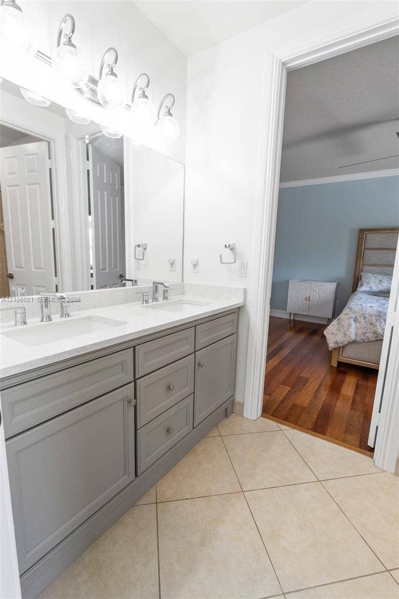 19510 S Coquina Way, Weston, FL 33332 Double vanity featuring a light-toned countertop, rectangular undermount sinks, polished chrome hardware, and grey Shaker-style cabinetry