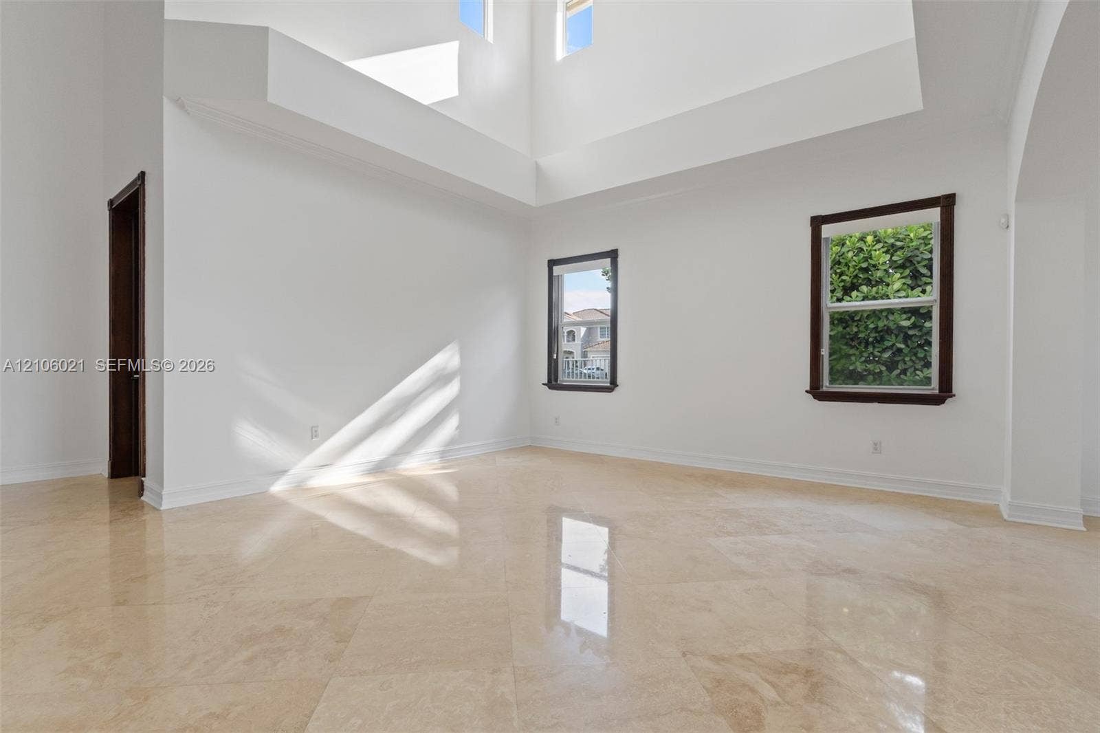 19510 S Coquina Way, Weston, FL 33332 High-ceilinged room featuring natural stone flooring, multiple windows with dark-finish frames, and recessed architectural wall detailing