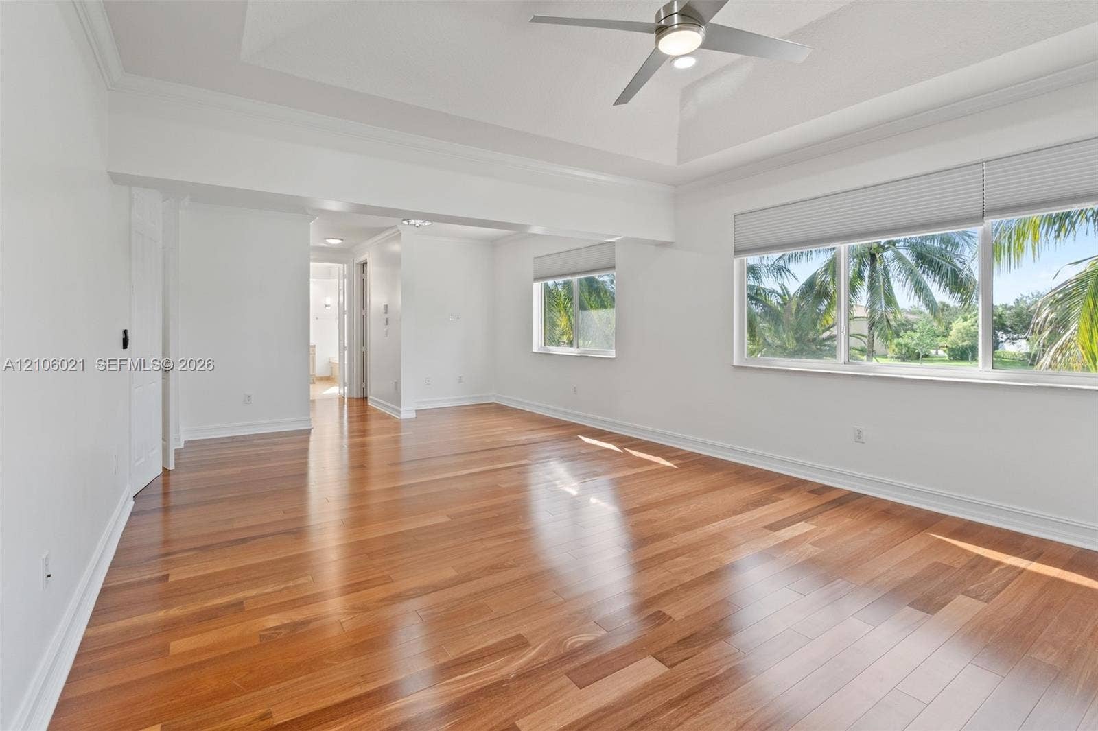 19510 S Coquina Way, Weston, FL 33332 Spacious interior featuring wood-finish flooring, recessed tray ceiling, large windows with pleated shades, and a ceiling fan
