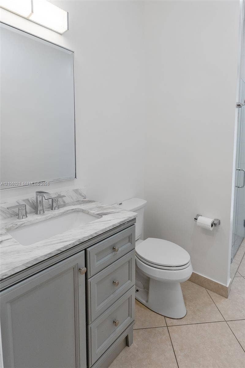 19510 S Coquina Way, Weston, FL 33332 Bathroom featuring a grey vanity with stone-top surface, undermount sink, framed mirror, and tiled flooring