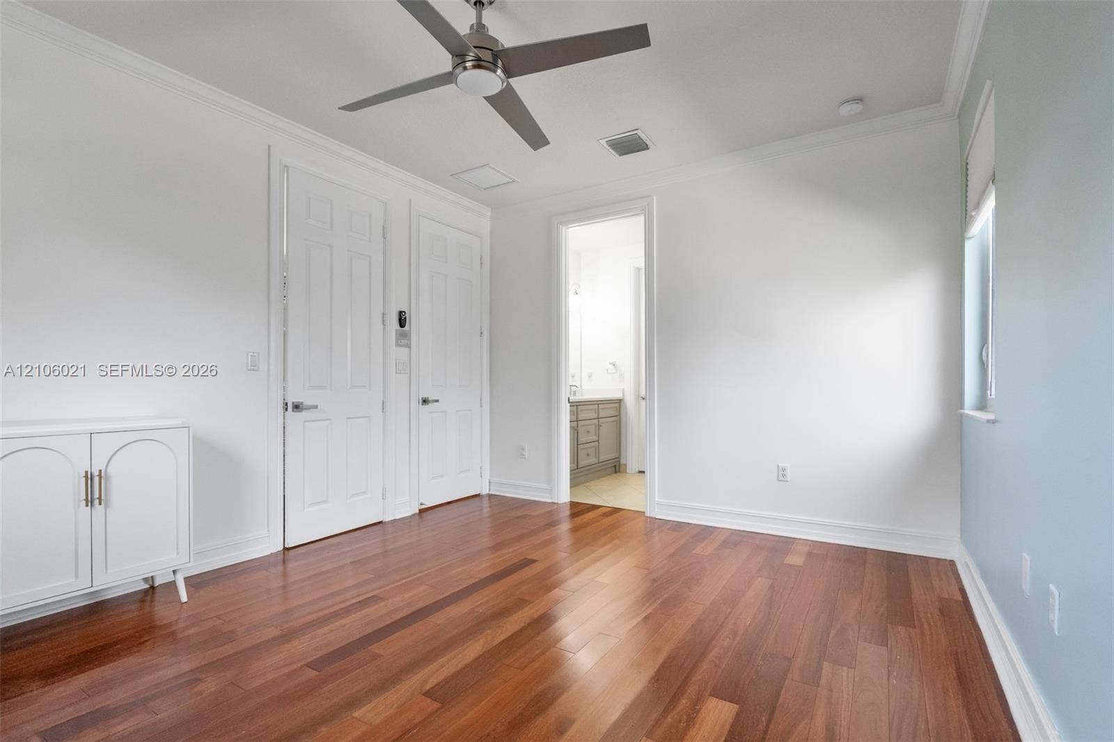 19510 S Coquina Way, Weston, FL 33332 Room featuring wood-finish flooring, crown molding, a ceiling fan, and two interior doors with arched-panel detailing