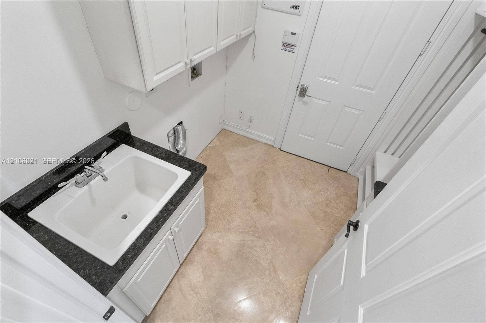 19510 S Coquina Way, Weston, FL 33332 Utility area featuring tile flooring, built-in white cabinetry, and a deep basin sink with a dark stone-finish countertop