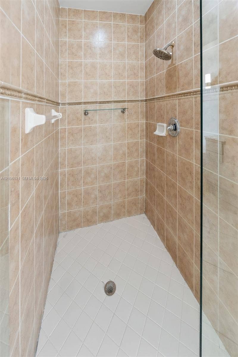 19510 S Coquina Way, Weston, FL 33332 Walk-in shower featuring floor-to-ceiling tile, decorative accent trim, glass door enclosure, and wall-mounted shower head