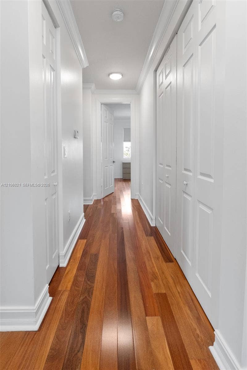 19510 S Coquina Way, Weston, FL 33332 Hallway featuring wood-finish flooring, white multi-panel doors, and crisp crown molding