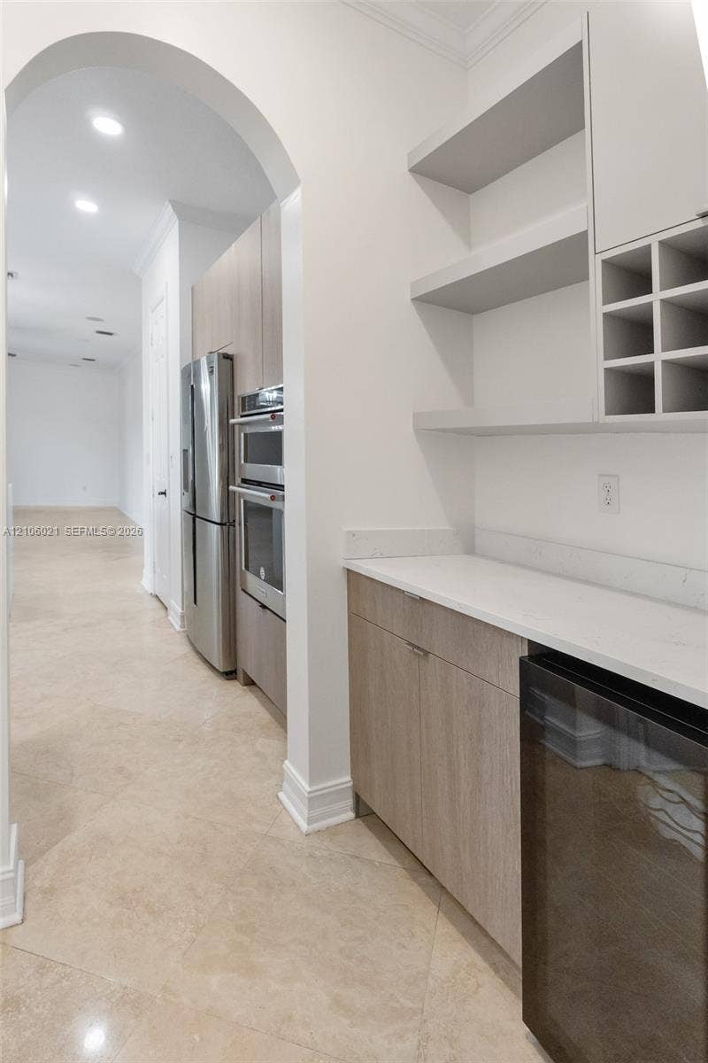 19510 S Coquina Way, Weston, FL 33332 Butlers pantry featuring wood-finish cabinetry, quartz countertops, open shelving, integrated wine rack, and a built-in beverage refrigerator