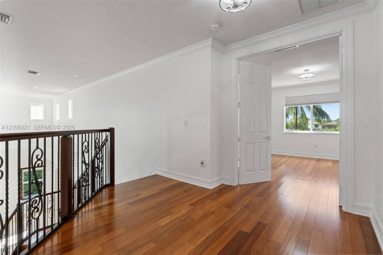 19510 S Coquina Way, Weston, FL 33332 Landing featuring wood-finish flooring, crown molding, wrought iron balusters, and dual-panel interior doors