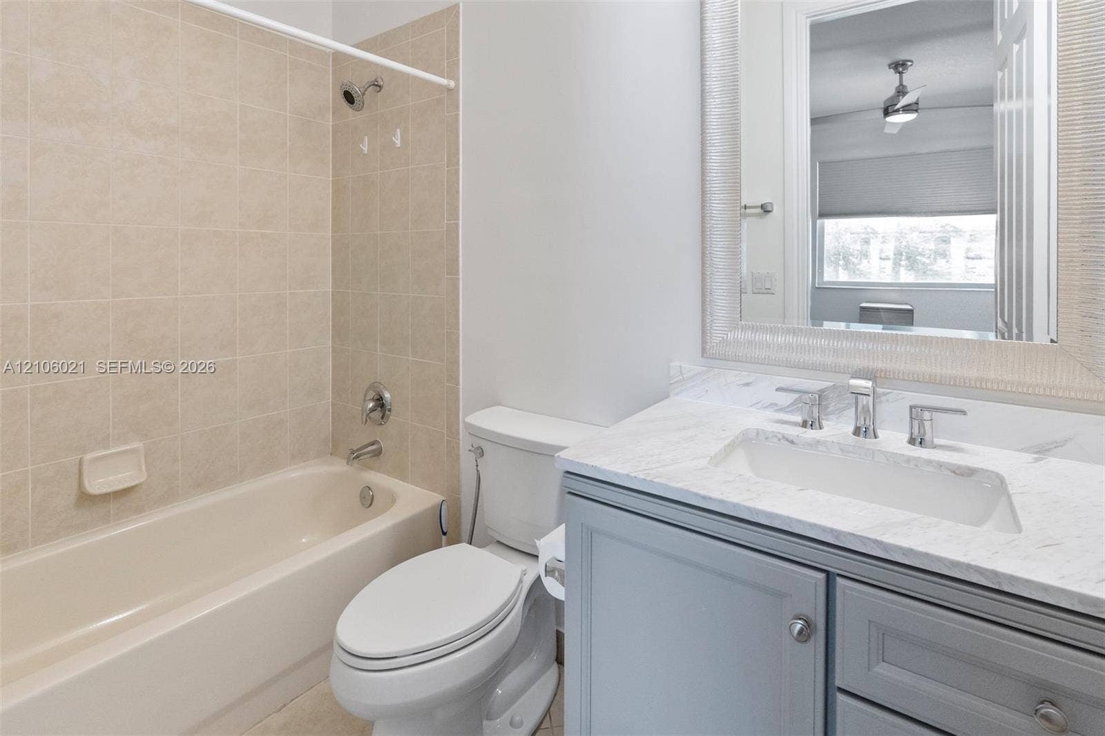 19510 S Coquina Way, Weston, FL 33332 Bathroom featuring a vanity with a stone-top counter, undermount sink, and chrome fixtures, complemented by a tiled bathtub surround and a framed wall mirror