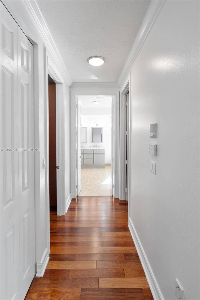 19510 S Coquina Way, Weston, FL 33332 Hallway featuring wood-finish flooring, crisp crown molding, and panel-style interior doors