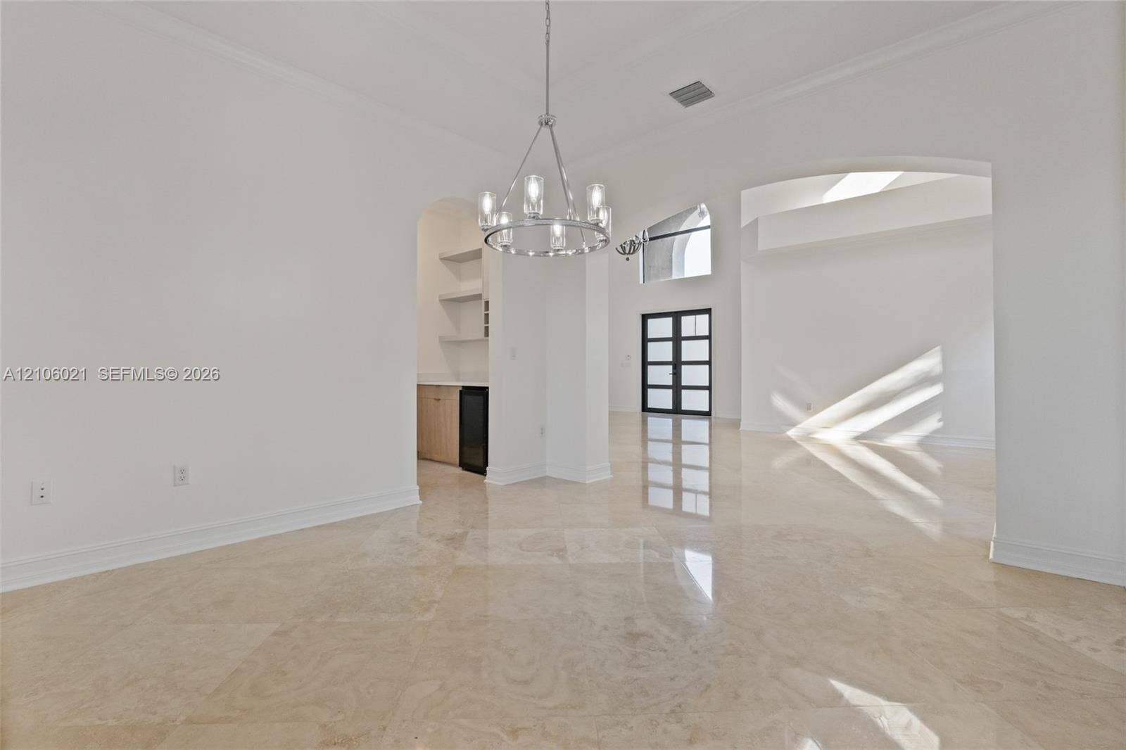 19510 S Coquina Way, Weston, FL 33332 Polished stone tile flooring, crown molding, multi-arm metal chandelier, and a built-in wet bar featuring stone countertops, cabinetry, and floating shelving