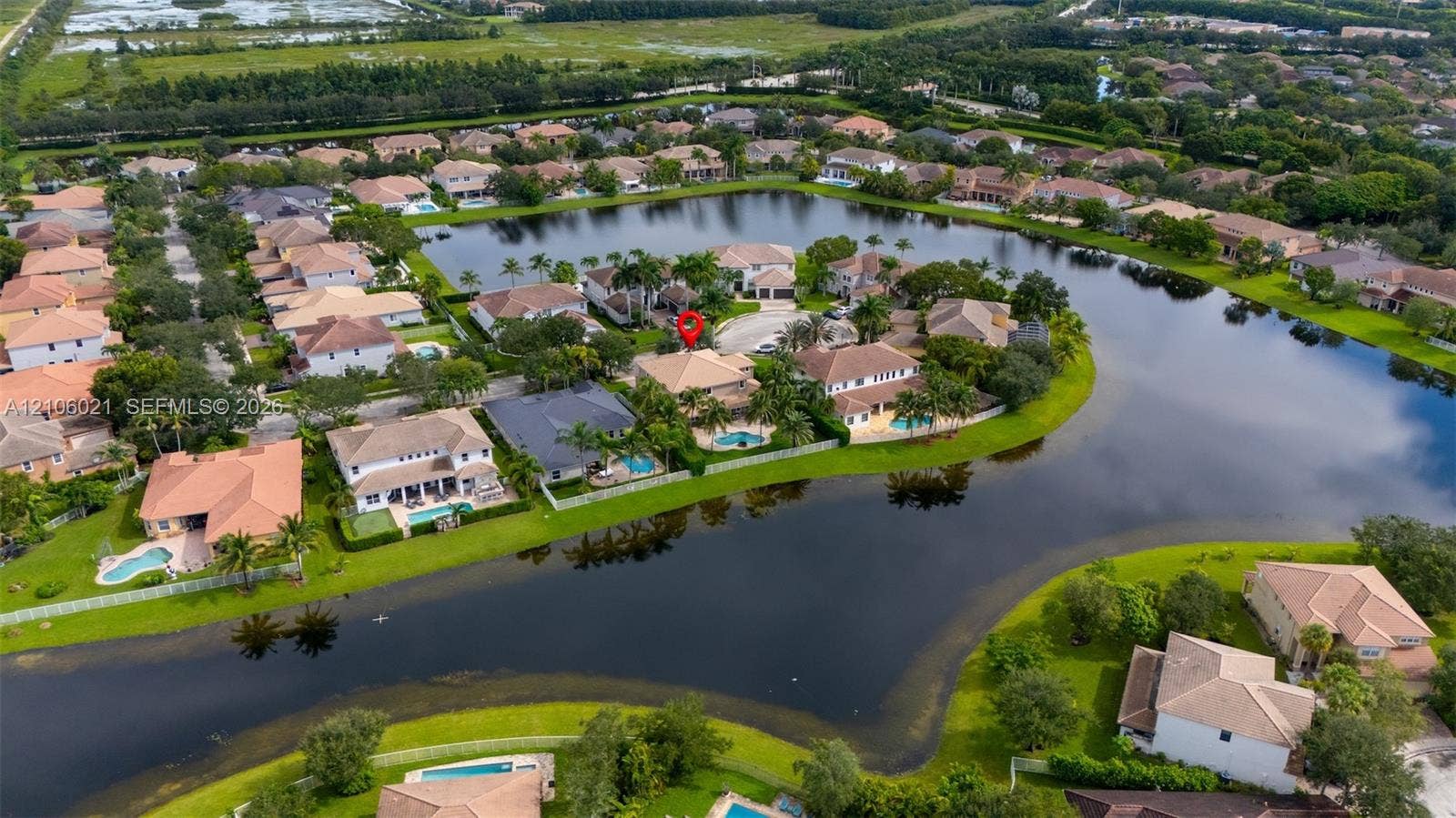 19510 S Coquina Way, Weston, FL 33332 Aerial perspective of waterfront property featuring a tile roof, an in-ground swimming pool, and established perimeter landscaping