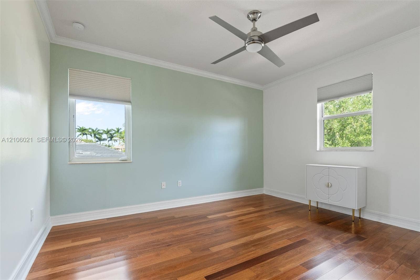 19510 S Coquina Way, Weston, FL 33332 Room featuring wood-finish flooring, a pale green accent wall, crown molding, double-pane windows with integrated blinds, and a contemporary ceiling fan