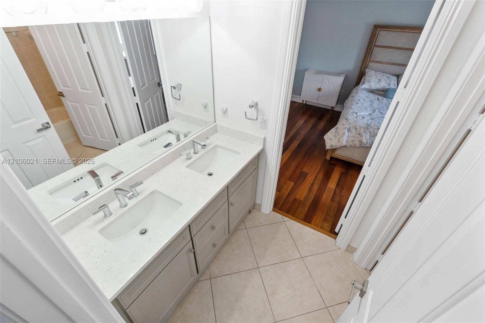19510 S Coquina Way, Weston, FL 33332 Dual-vanity bathroom featuring light-toned cabinetry, quartz countertops, undermount sinks, and ceramic tile flooring