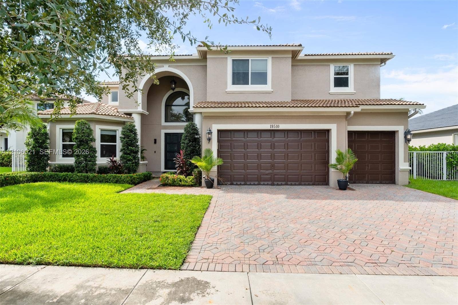 19510 S Coquina Way, Weston, FL 33332 Two-story stucco exterior with a tiled roof, arched entryway, brick-paver driveway, and a three-car garage