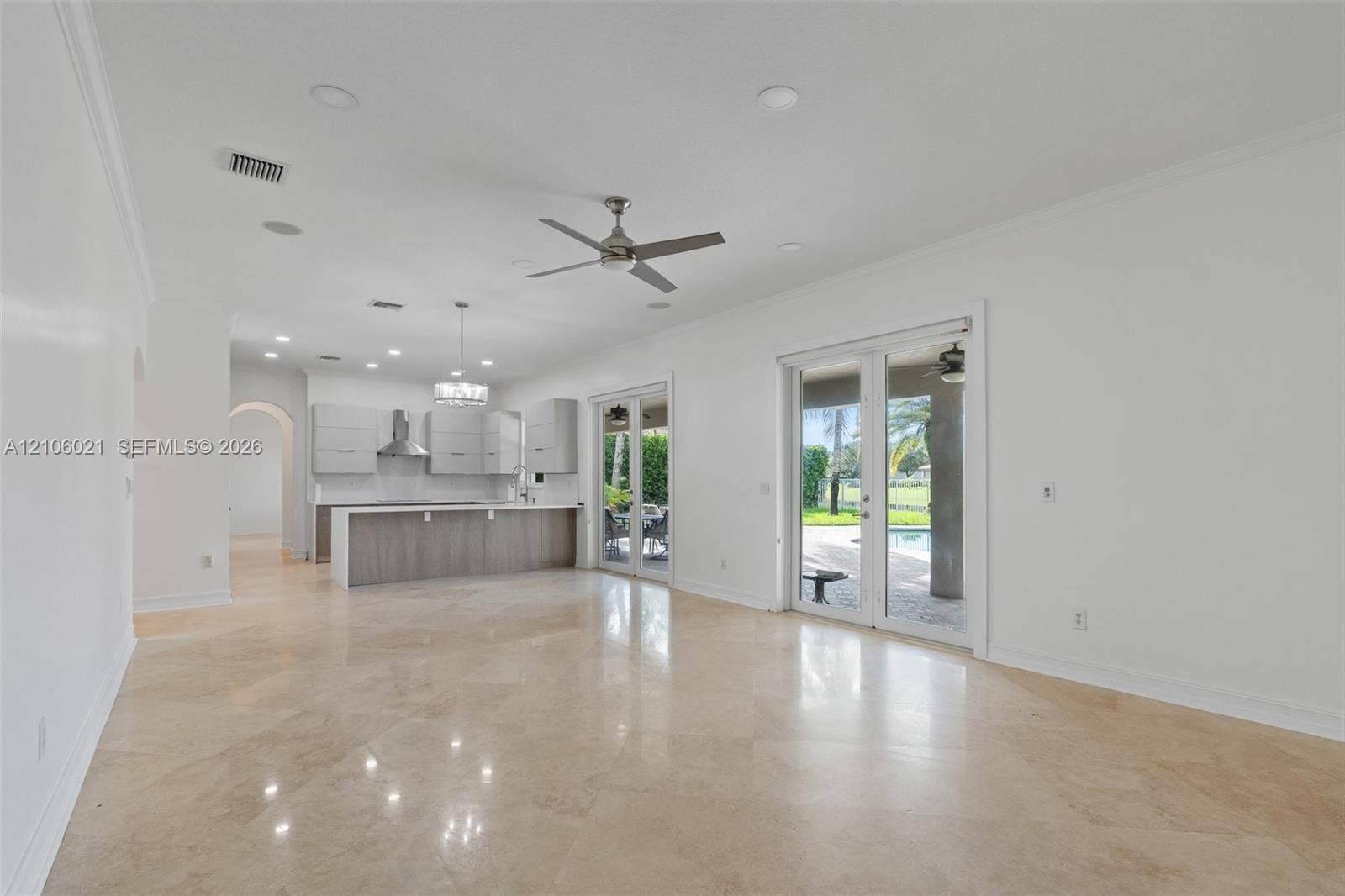 19510 S Coquina Way, Weston, FL 33332 Open-concept interior featuring stone flooring, recessed lighting, a modern kitchen with a waterfall-edge island, and glass sliding doors