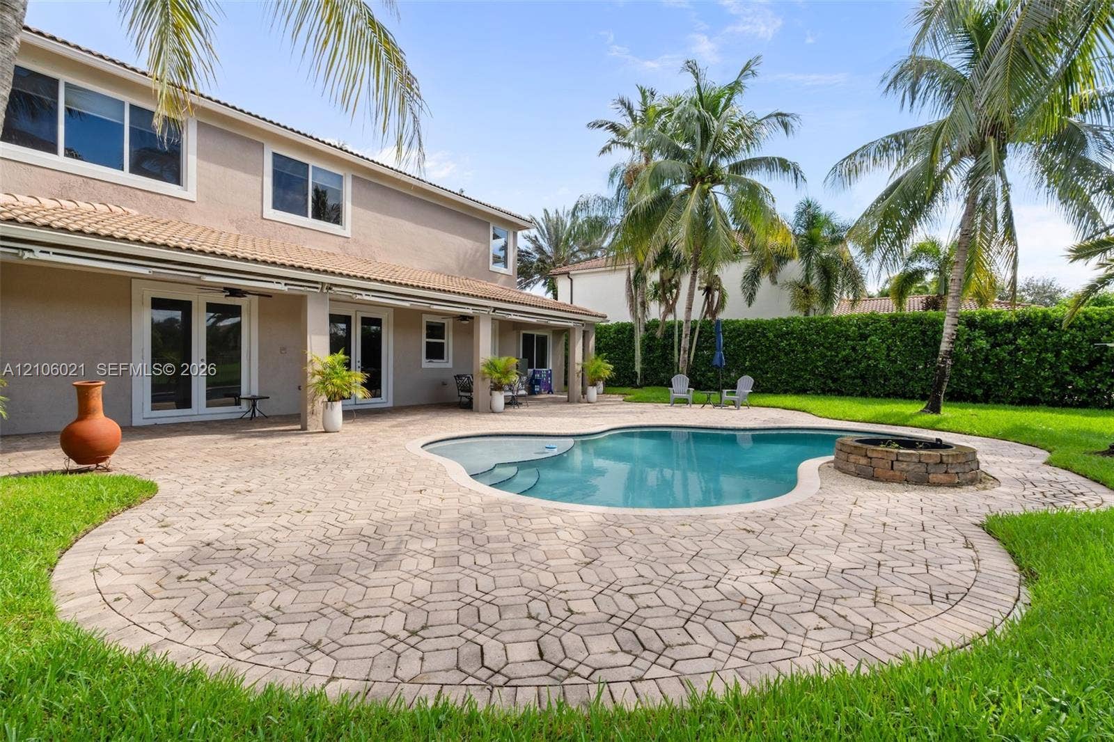 19510 S Coquina Way, Weston, FL 33332 Custom-shaped swimming pool with an integrated stone fire pit, expansive paver patio, and covered porch