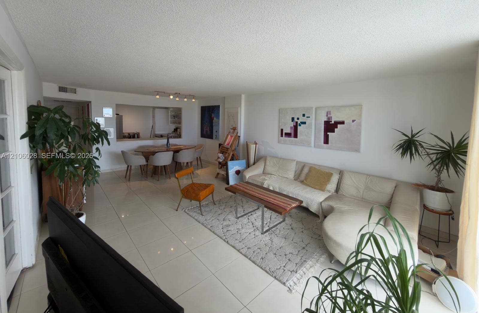 2780 NE 183rd Street, #1605, Aventura, FL 33160 Open-concept living space featuring large-format tile flooring, a pass-through wall opening, and recessed ceiling track lighting