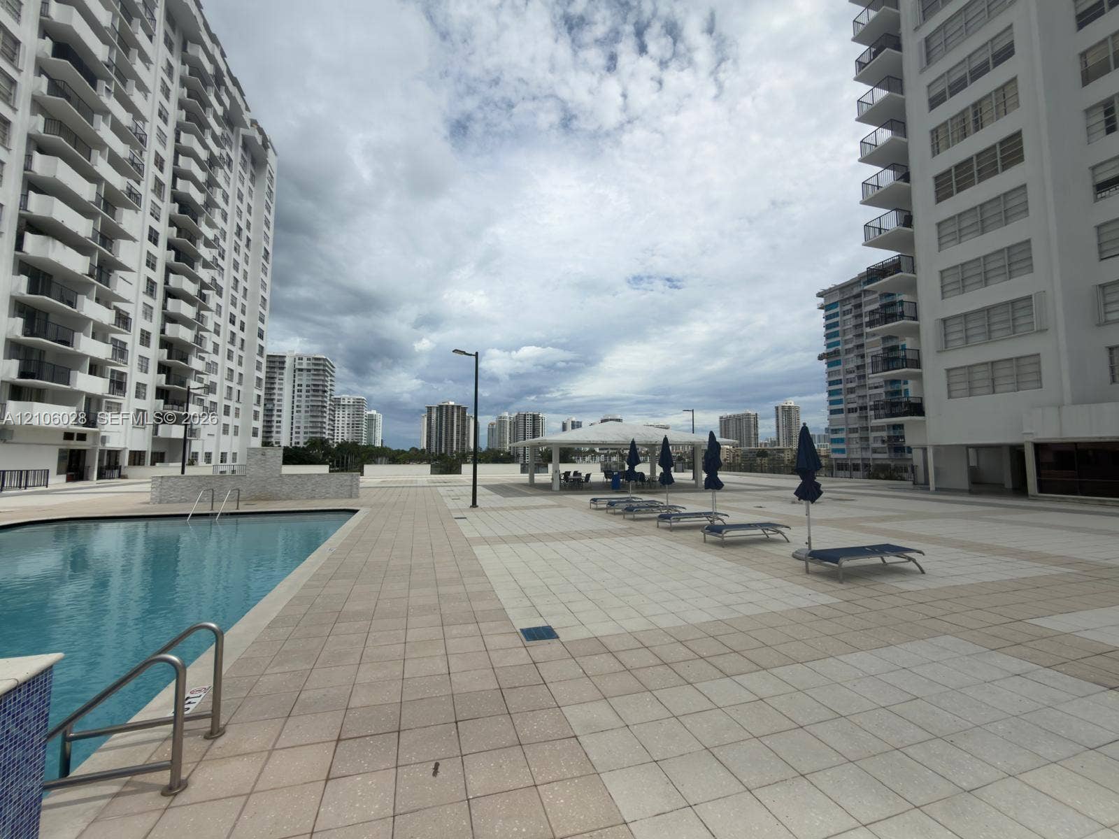 2780 NE 183rd Street, #1605, Aventura, FL 33160 Outdoor pool with tiled surround, stone-clad water feature, and covered pavilion area