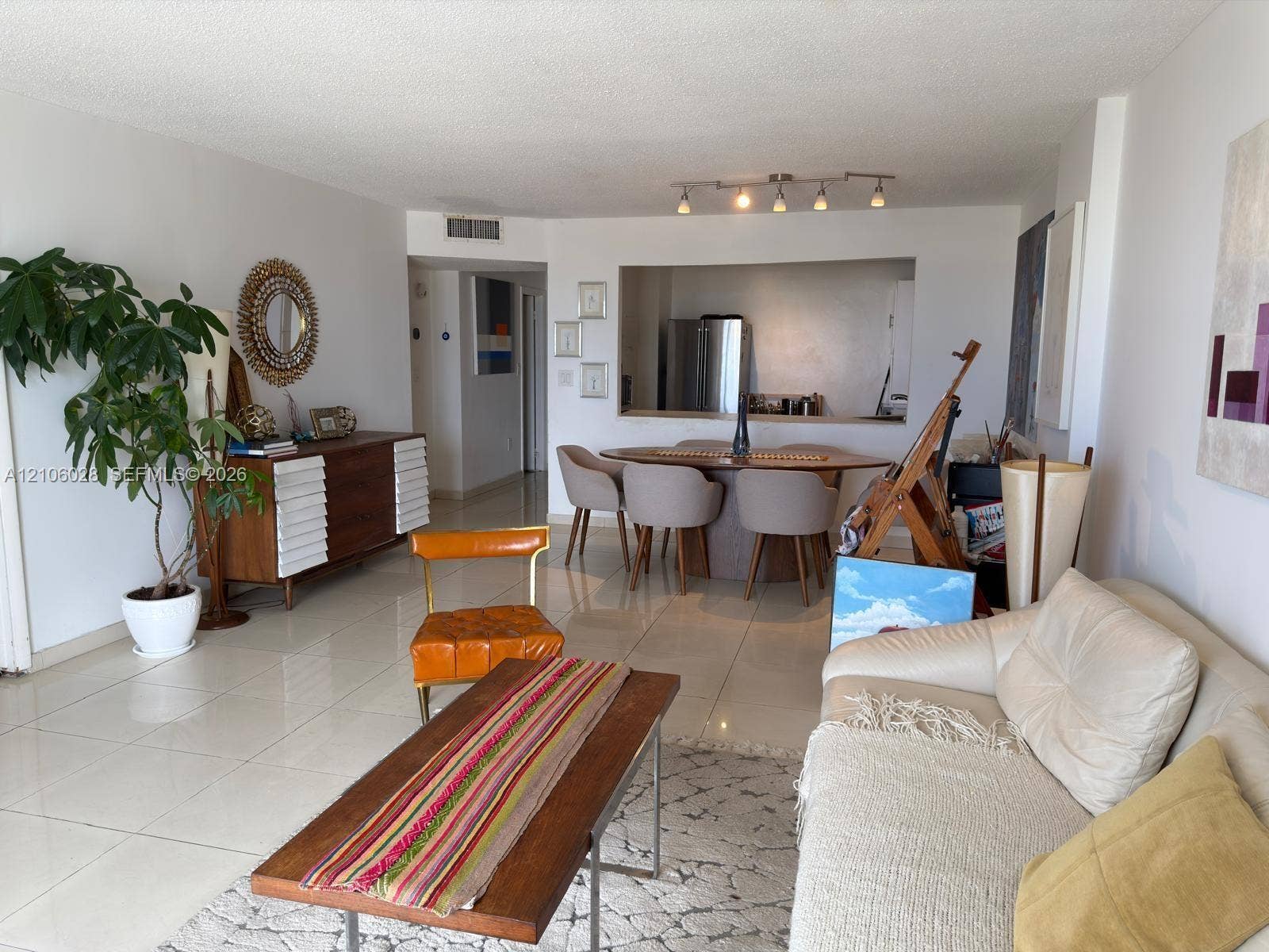 2780 NE 183rd Street, #1605, Aventura, FL 33160 Open-concept area featuring light-toned tile flooring, neutral wall finishes, a multi-head track lighting fixture, and a pass-through kitchen opening