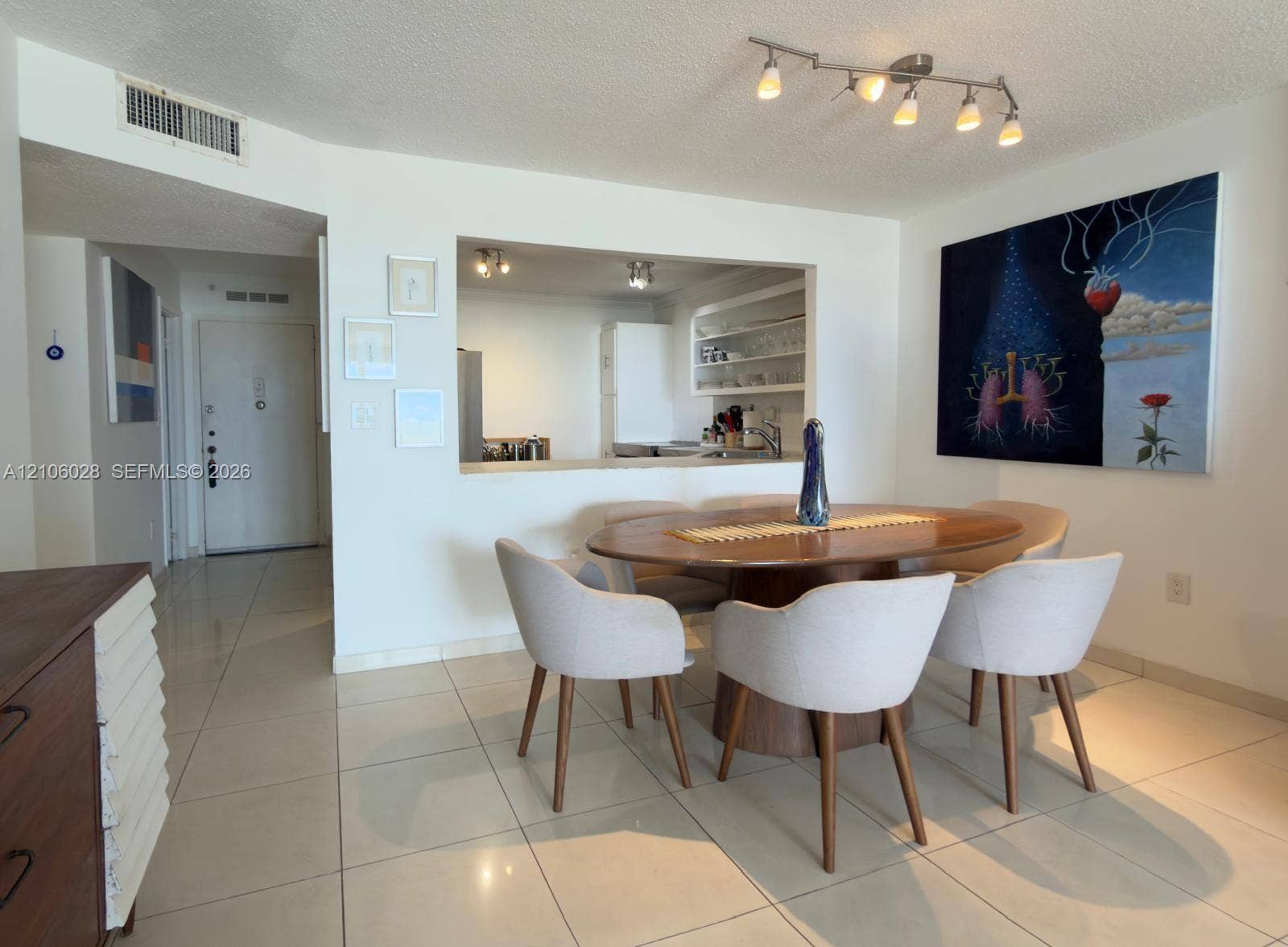 2780 NE 183rd Street, #1605, Aventura, FL 33160 Dining area featuring large-format ceramic tile flooring, a pass-through window to the kitchen, and a six-light track fixture