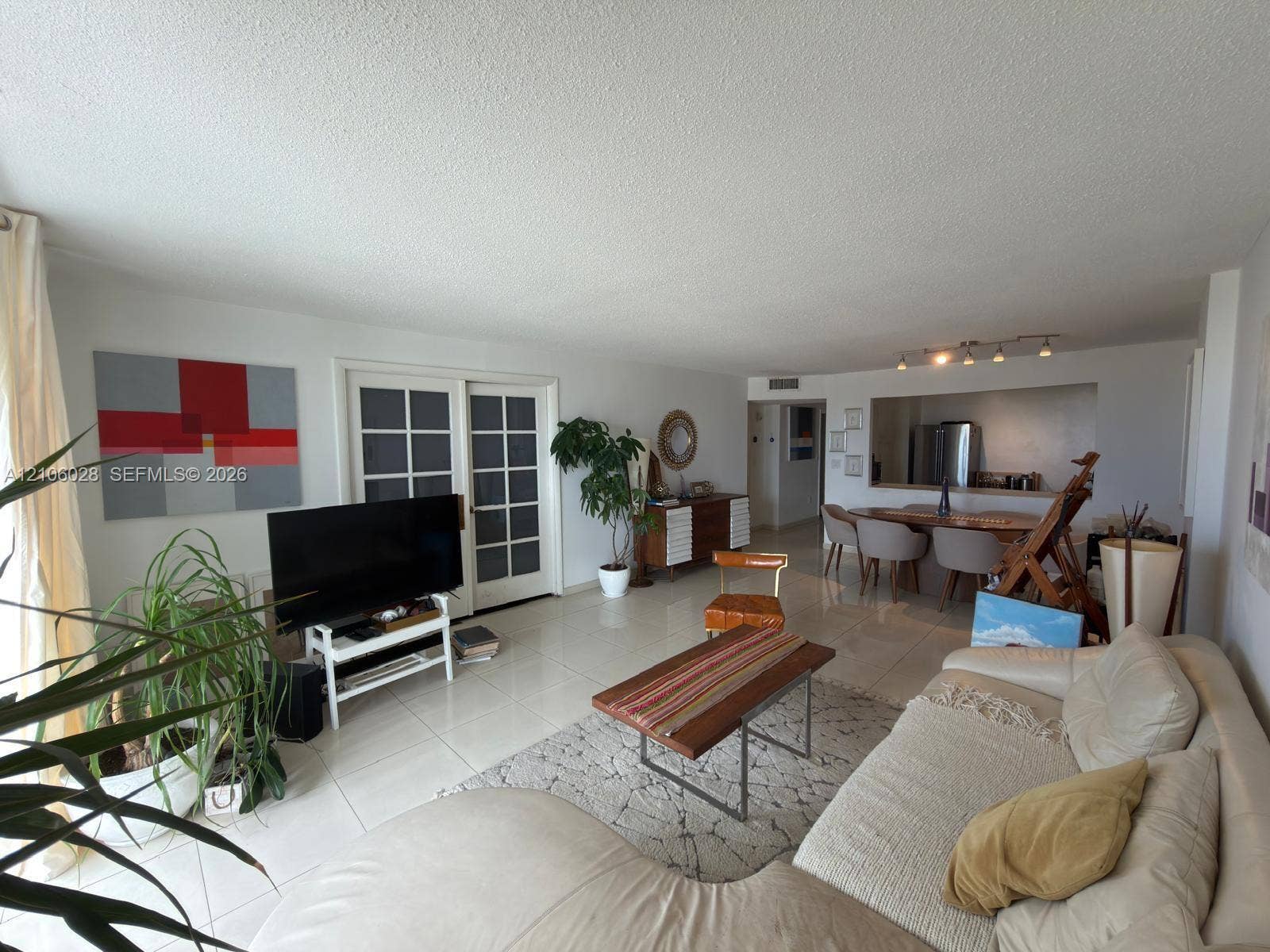 2780 NE 183rd Street, #1605, Aventura, FL 33160 Living area featuring large-format tile flooring, multi-pane glass sliding doors, and an open pass-through window to the kitchen area