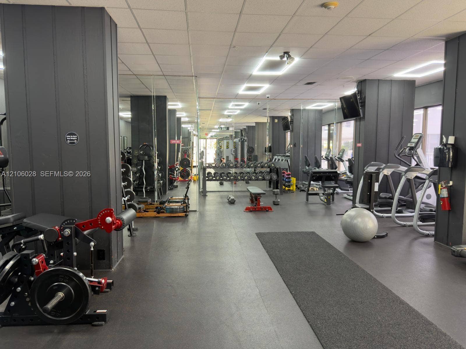 2780 NE 183rd Street, #1605, Aventura, FL 33160 Fitness facility featuring full-wall mirrors, recessed ceiling lighting, dark-toned vertical wall paneling, and rubberized flooring