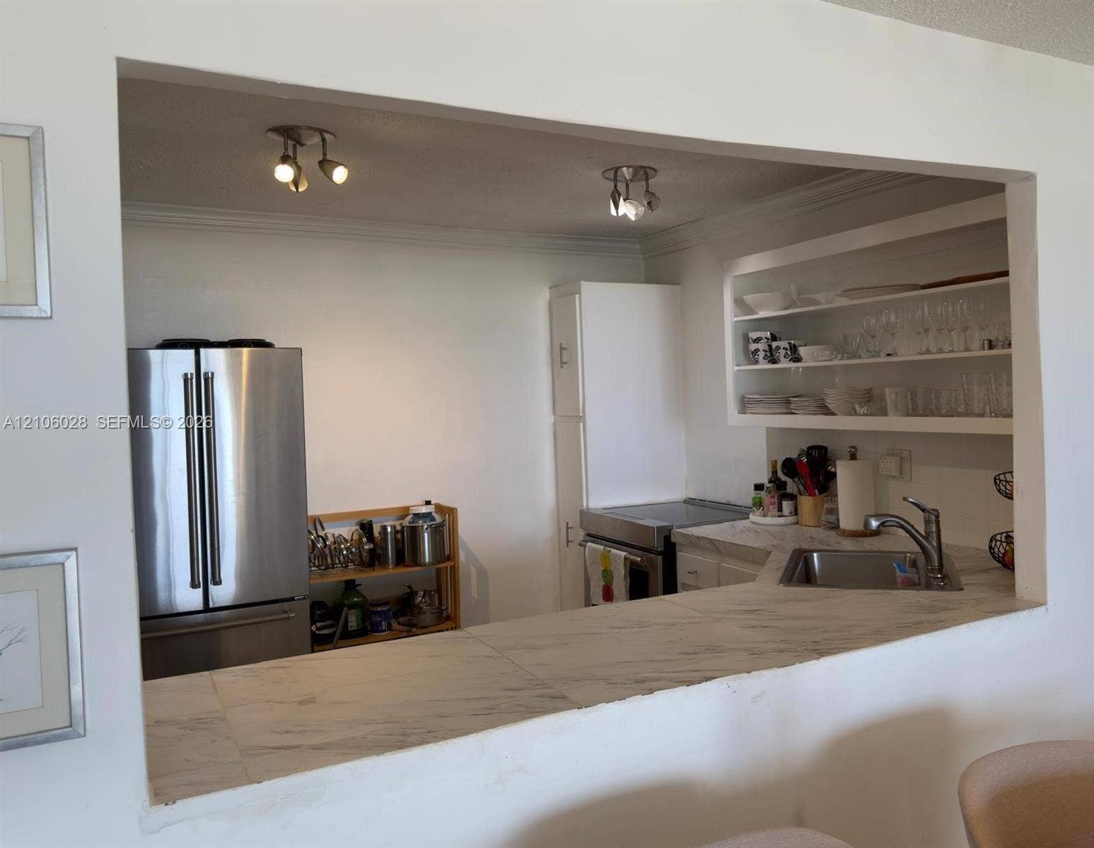 2780 NE 183rd Street, #1605, Aventura, FL 33160 Kitchen featuring a stone-surface pass-through counter, stainless steel refrigerator, built-in open shelving, and dual multi-directional track lighting